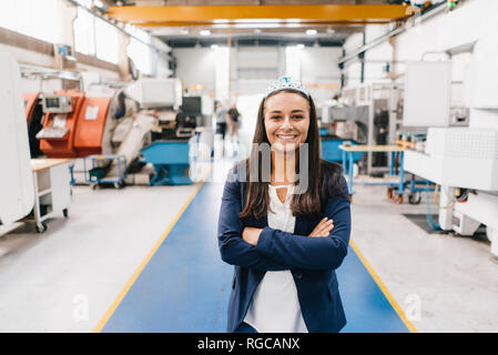 Selbstbewusste Frau, die in High-Tech-Unternehmen, die in der Fabrik Workshop mit gekreuzten Armen Stockfoto
