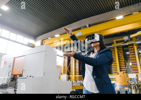 Junge Frau arbeitet im Versandlager, VR-Brille tragen Stockfoto