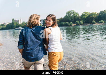 Glückliches junges Paar in Liebe zu Fuß am Flußufer Stockfoto