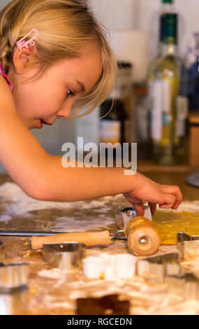 Kleines Mädchen schneiden Cookies mit Cookie Cutter in der Weihnachtszeit Stockfoto