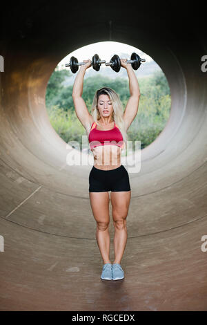 Athletische Frau tun Gewicht Training in einer Röhre stehend Stockfoto