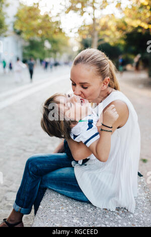 Mutter sitzt auf der bank, beim Kuscheln mit Ihrem Sohn Stockfoto