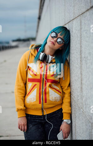 Porträt der jungen Frau mit gefärbtem Haar zu tragen blau verspiegelten Sonnenbrillen und modische Kapuzenjacke Stockfoto