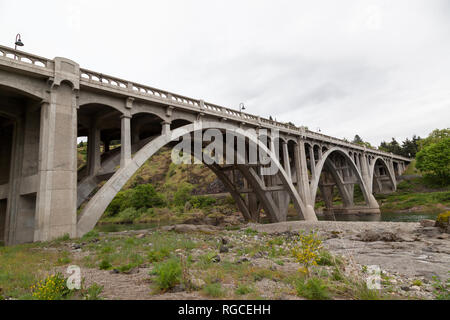 Eine konkrete Bogenbrücke überspannt das grüne Wasser im Süden Umpqua River in Oregon. Stockfoto