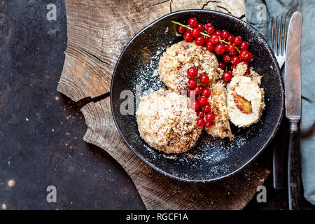 Pflaume gefüllte süße Knödel mit Kokosnuss - Zimt Kruste und rote Johannisbeeren Stockfoto