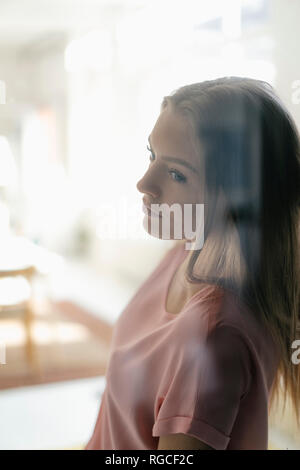 Porträt der nachdenkliche junge Frau hinter der Glasscheibe Stockfoto