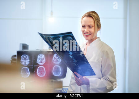 Lächelnd weibliche Arzt suchen an x-ray Image Stockfoto