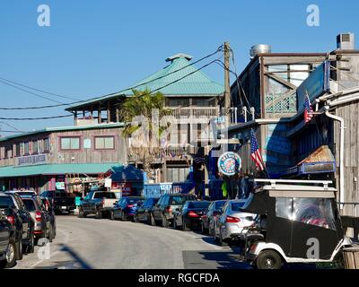 Autos entlang Einbahnstraße vor der Unternehmen geparkt/Restaurants auf der Station Street, 1St Street, Cedar Key, Florida, USA. Stockfoto