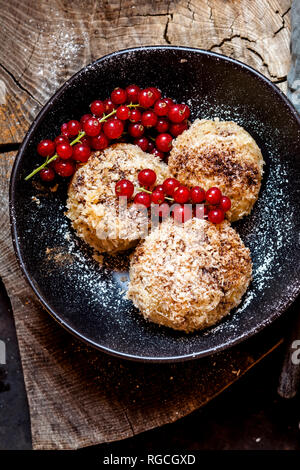 Pflaume gefüllte süße Knödel mit Kokosnuss - Zimt Kruste und rote Johannisbeeren Stockfoto