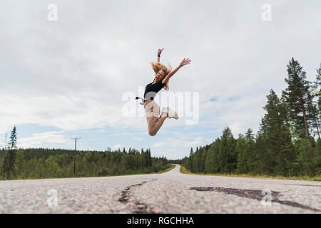 Finnland, Lappland, quirlige junge Frau in ländlichen Landschaft springen Stockfoto