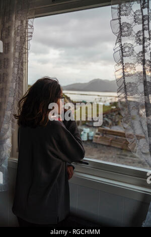 Junge Frau aus Fenster Stockfoto