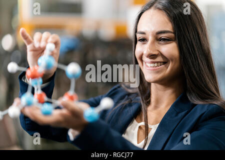 Selbstbewusste Frau, die in High-Tech-Unternehmen, holding Molekülmodell Stockfoto