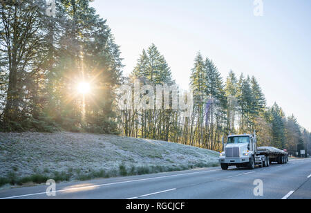 Big Rig Tag cab professionelle Motorhaube leistungsfähige Semi Truck Transport gewerbliche Ladung auf Flachbett Auflieger abgedeckt und auf Winte Stockfoto