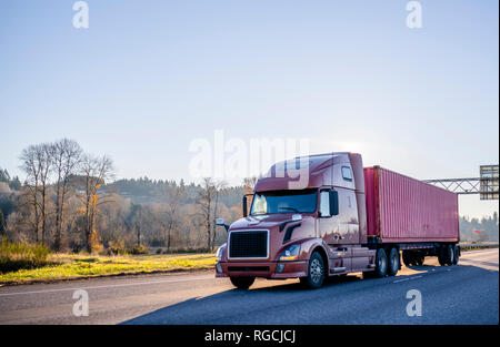 Big Rig braun professional Motorhaube leistungsfähige Semi Truck Transport Container mit gewerbliche Ladung auf Flachbett Auflieger auf Wint Stockfoto