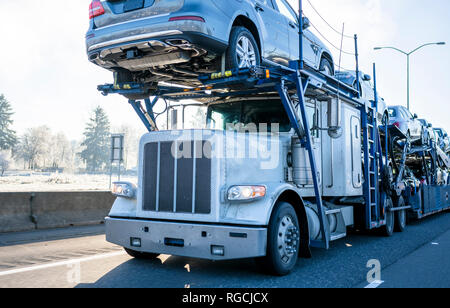 Big Rig car Hauler professionelle Motorhaube leistungsfähige Semi Truck Autos transportieren auf zwei Ebenen industrielle Auflieger auf Winter frostige Straße mit dem Fahren Stockfoto