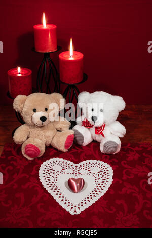 Herz shapped dollie und Edelstein, drei rote Kerzen in Metallhalterungen und Red Rose, zwei Teddybären auf hölzernen Tisch. Stockfoto