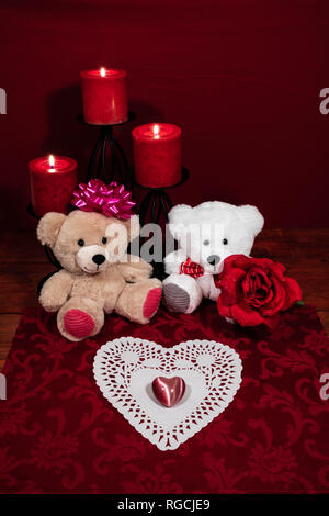 Herz shapped dollie und Edelstein, drei rote Kerzen in Metallhalterungen und Red Rose, zwei Teddybären auf hölzernen Tisch. Stockfoto