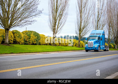 Klassische Motorhaube kommerziellen Transport pro-amerikanischen Big Rig blau Long Haul Semi Truck Traktor fahren auf der Straße mit Bäumen und Sträuchern für die rechtzeitige a Stockfoto