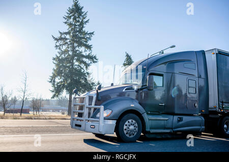 Dunkelgrau Big Rig amerikanischen Motorhaube, modernes, stilvolles Semi Truck mit starken Grill schutz Aluminium Stoßfänger und überdachte Auflieger auf dem breiten mu gehen Stockfoto