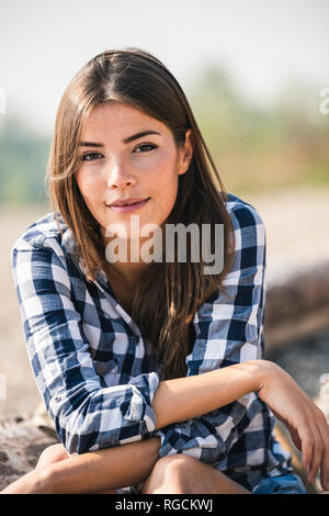 Portrait von lächelnden jungen Frau sitzt im Freien Stockfoto