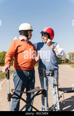 Zwei alte Freunde das Tragen von Schutzhelmen, die Vorbereitung auf einen Rollator Rennen Stockfoto