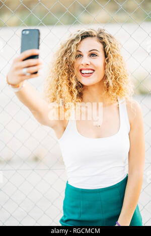 Porträt der blonde junge Frau unter selfie mit Handy Stockfoto