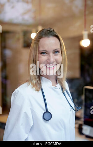 Portrait von lächelnden Frau Doktor mit Stethoskop hinter Fensterglas Stockfoto