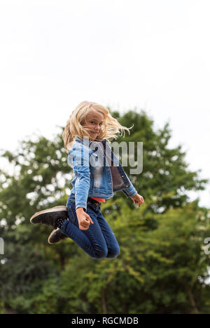 Portrait von blondes Mädchen springen in die Luft, Stockfoto