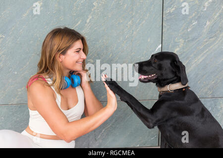 Glückliche junge Frau mit ihrem schwarzen Hund Stockfoto