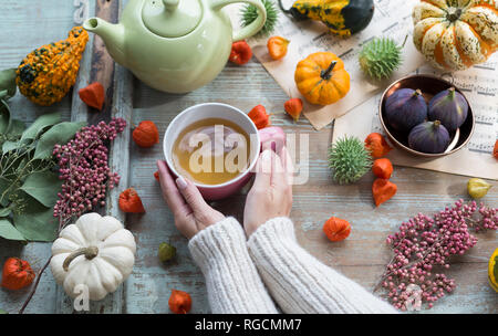 Frau wärmen Ihre Hände auf Tasse Tee im Herbst Stockfoto
