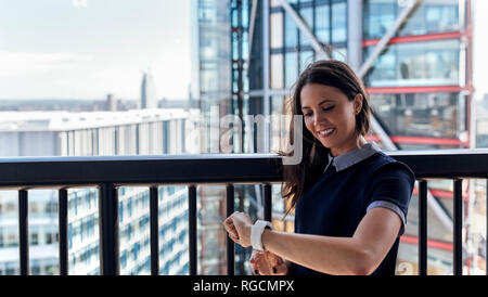 UK, London, lächelnde Frau mit smartwatch auf der Dachterrasse Stockfoto