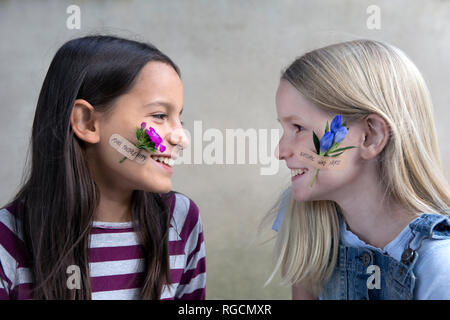 Zwei lächelnde Mädchen mit Blume Köpfe auf ihren Backen Stockfoto