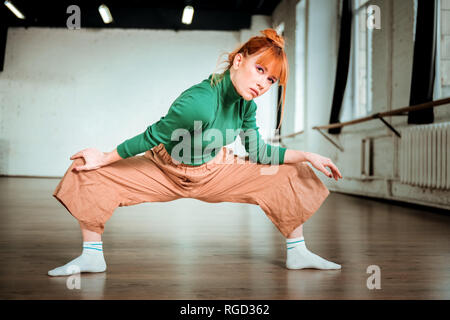 Gut aussehende slim Yoga Trainer in einem grünen Rollkragen suchen konzentriert Stockfoto