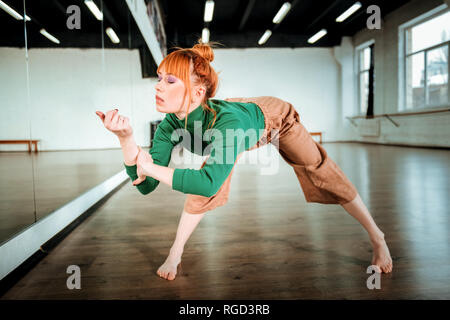 Rothaarige professionelle Yogalehrer in einer grünen Rollkragen in der Asana Stockfoto