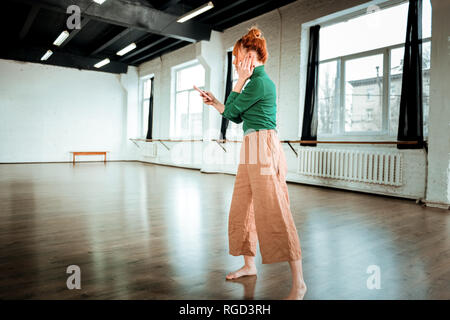 Rothaarige professionelle Yogalehrer in einer grünen Rollkragen suchen aufmerksam Stockfoto