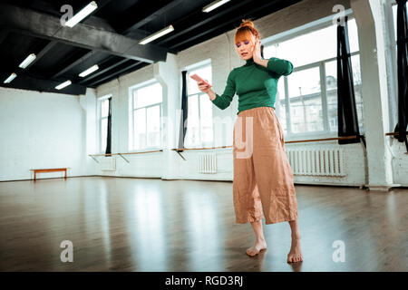 Rothaarige professionelle Yogalehrer mit Haar bun aufmerksam zuhören Stockfoto