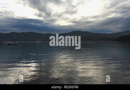 Ansicht der Gewitterwolken kontrastieren mit hellen Abendlicht im Wasser von Akaroa, Neuseeland spiegelt sich auf der touristischen Banks Halbinsel. Stockfoto