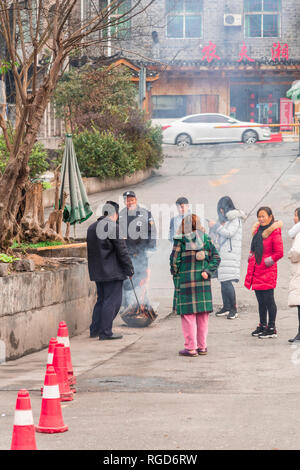 FENGHUANG, Hunan, China - 12. Dezember 2018: Nicht identifizierte Personen Erwärmung in der Nähe von einem Brand in der Straße in der Altstadt von Phoenix (antike Stadt Fenghu Stockfoto