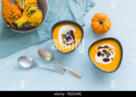 Zwei Schalen mit hausgemachten Hokkaido Kürbis Suppe, garniert mit Sahne, Kürbiskernöl und Kürbiskerne Stockfoto