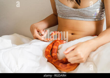 Junge Frau im Bett mit einer Schlange Stockfoto