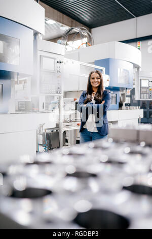 Selbstbewusste Frau, die in High-Tech-Unternehmen, die in der Fabrik Workshop mit gekreuzten Armen Stockfoto