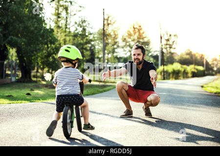 Vater Unterstützung von kleinen Sohn mit dem Fahrrad Stockfoto