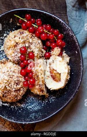 Pflaume gefüllte süße Knödel mit Kokosnuss - Zimt Kruste und rote Johannisbeeren Stockfoto