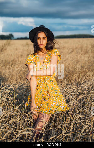 Porträt der jungen Frau Sommer Kleid mit Blumenmuster und einem Hut tanzen im Maisfeld Stockfoto