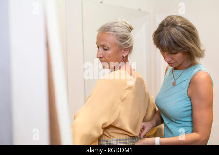 Shop Assistant hilft älteren Frau in einer Boutique Stockfoto