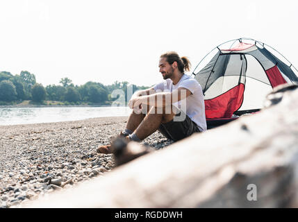 Junge Mann in einem Zelt am Ufer sitzen Stockfoto