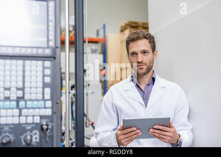 Mitarbeiter Kontrolle der Fertigung Maschinen in High Tech Unternehmen, indem Sie digitale Tablet Stockfoto