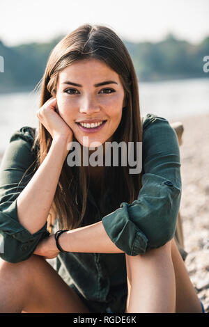 Portrait von lächelnden jungen Frau sitzt im Freien Stockfoto