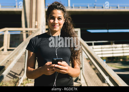 Porträt der sportliche junge Frau mit einer Unterbrechung Musik hören Stockfoto