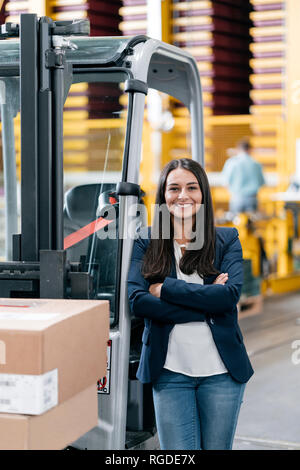 Selbstbewusste Frau im Logistikzentrum, mit verschränkten Armen Stockfoto